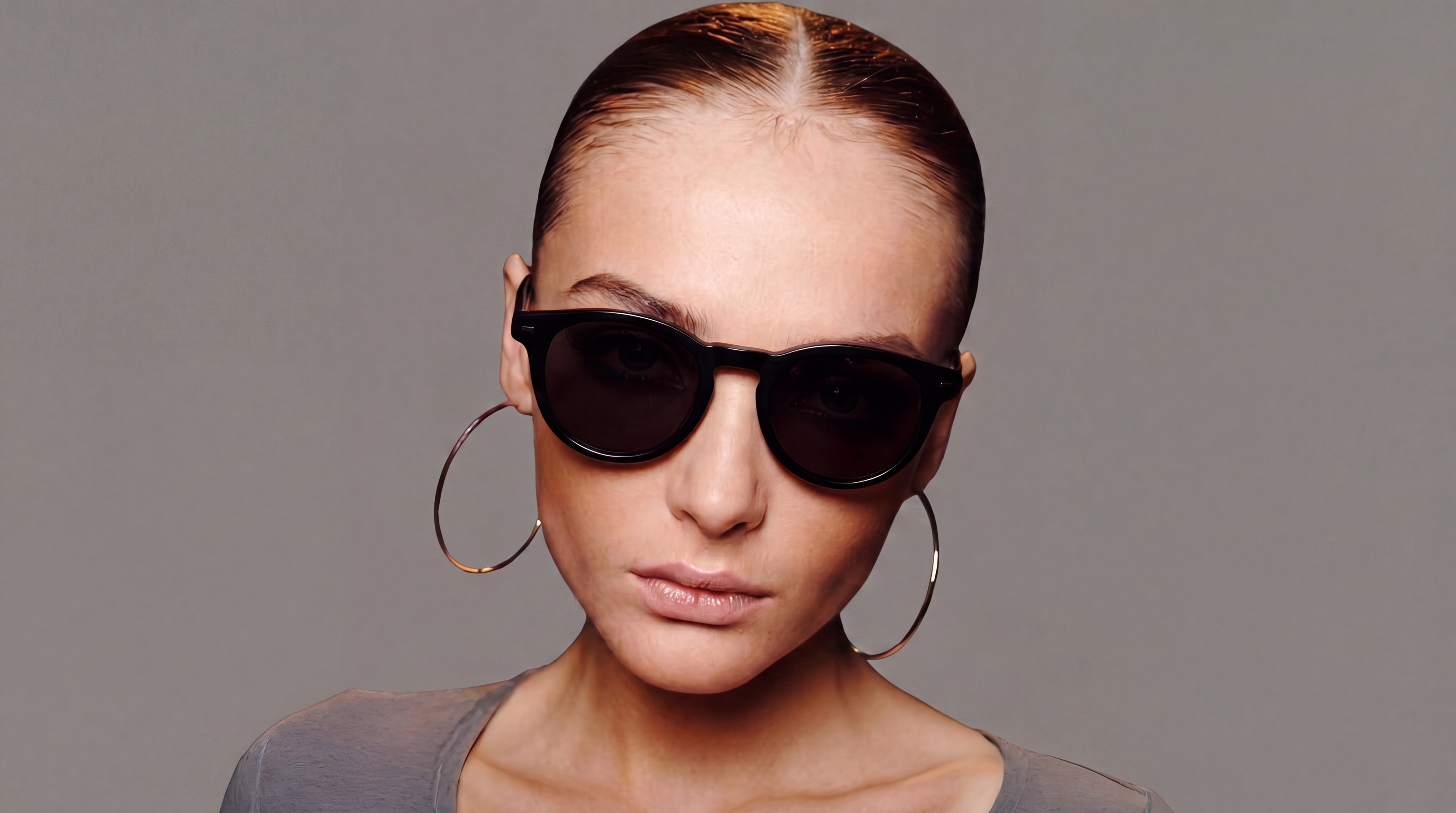Model wearing black designer sunglasses against a neutral studio backdrop